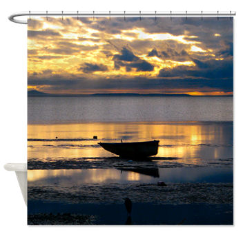 A rowboat sits stranded on the beach at low tide in Birch Bay with the rays of a setting sun painting the scene with dramatic touches